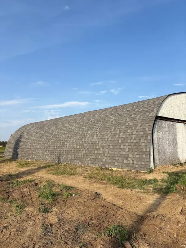 A quonset roof shingled in grey from the ground up to the crown